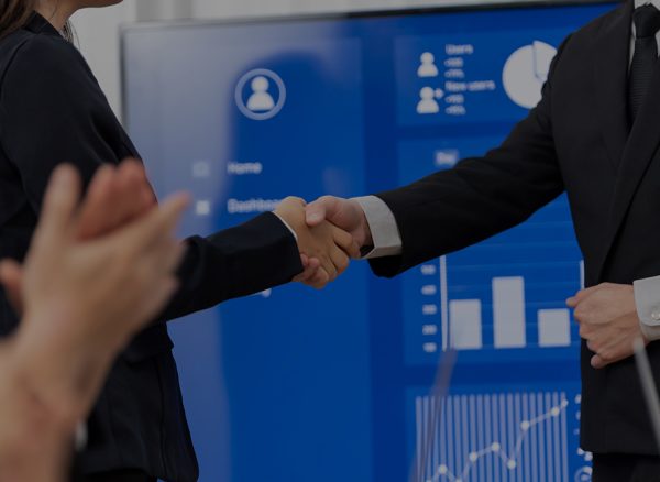 Closeup office worker shake hand business team leader manager for strong teamwork in office to promote harmony concept after successful agreement or meeting with dashboard report on screen background.