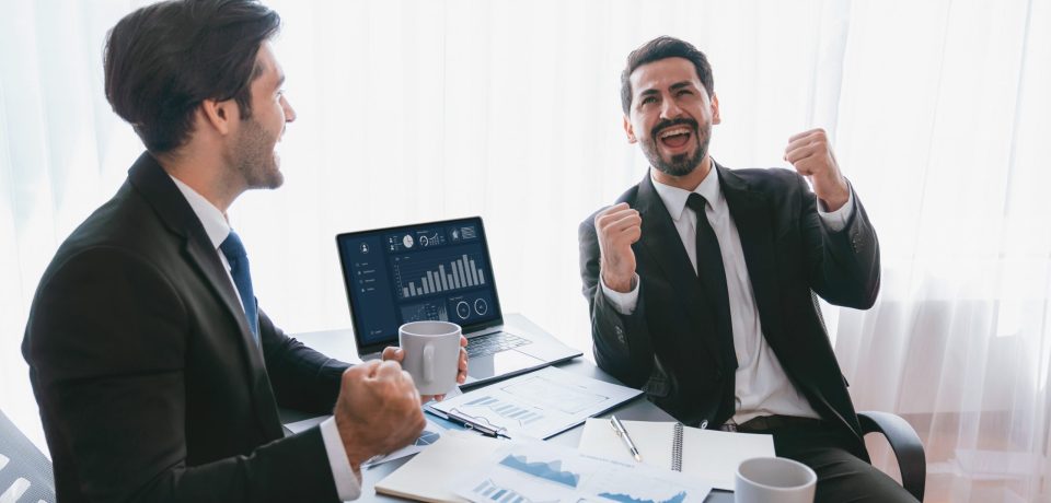 two-men-sitting-table-with-laptops-papers-table two-men-sitting-table-with-laptops-papers-table