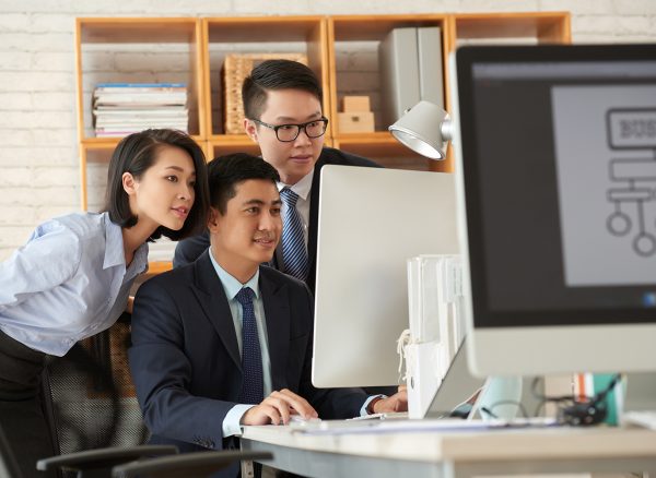 Team of business people gathered at computer in office