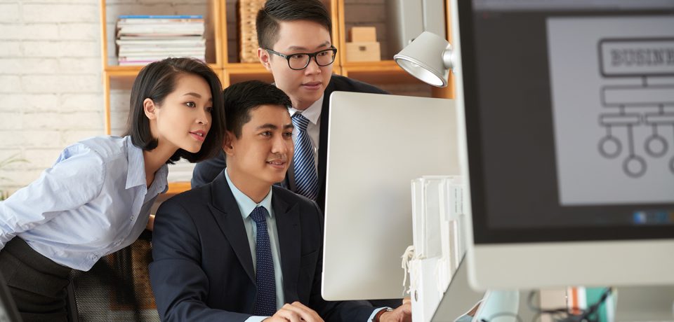 Team of business people gathered at computer in office