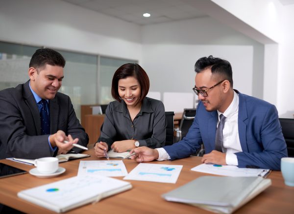 multiethnic-male-female-colleagues-sitting-office-discussing-charts-meeting