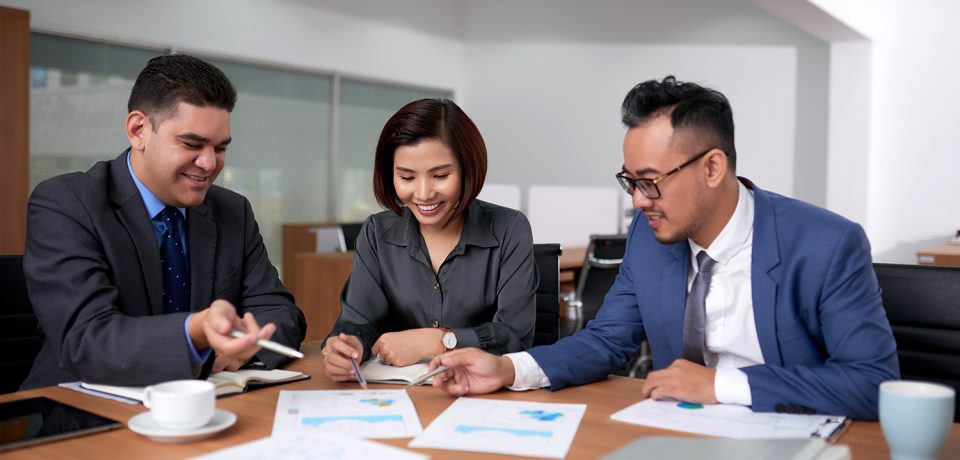 multiethnic-male-female-colleagues-sitting-office-discussing-charts-meeting