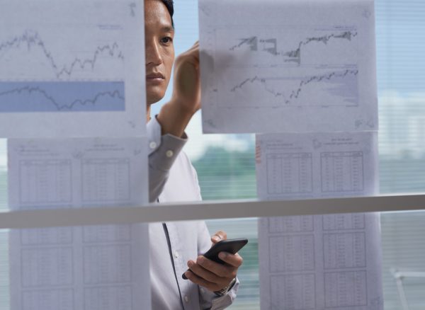 Analyzing financial information Businessman taking notes on financial charts hanging on the wall
