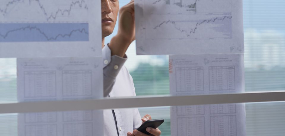 Businessman taking notes on financial charts hanging on the wall